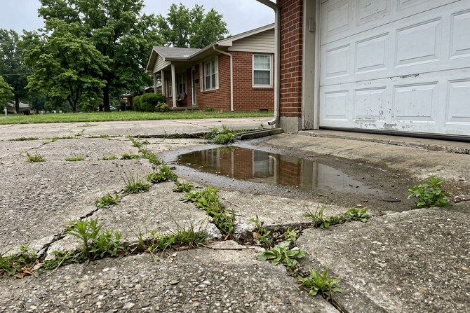 Cracked and sunken concrete driveway corner with water pooling